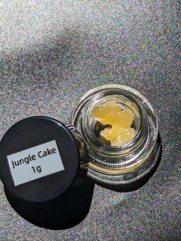 Close-up of Jungle Cake live resin concentrate in a glass container, offering a potent cannabis experience with rich flavors and a balanced hybrid profile.