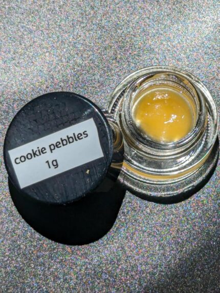 Close-up of Cookie Pebbles Live Resin concentrate in a glass container, offering sweet berry flavors and a potent cannabis experience.